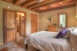 Experience rustic charm in this cozy bedroom featuring exposed wooden beams and a warm, inviting color palette.