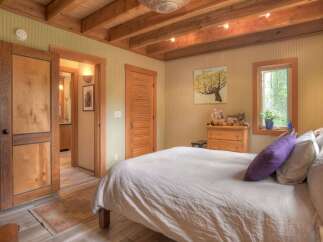 Experience rustic charm in this cozy bedroom featuring exposed wooden beams and a warm, inviting color palette.