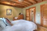 Experience rustic charm in this inviting bedroom, featuring exposed wooden beams on the ceiling and a cozy, light green paneled wall.