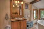 This charming bathroom features a rustic wooden vanity with a mosaic tile countertop and a deep basin sink.