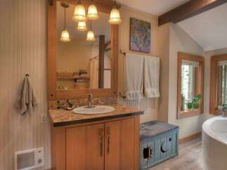 This charming bathroom features a rustic wooden vanity with a mosaic tile countertop and a deep basin sink.