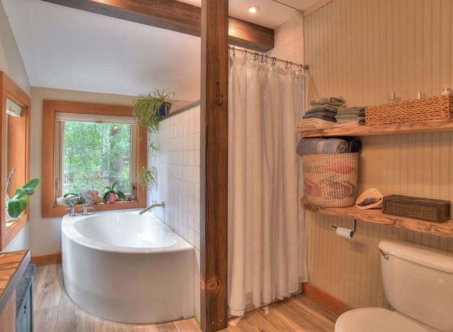 Experience tranquility in this charming bathroom featuring a deep soaking tub with a picturesque window view of lush greenery.