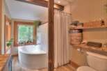 Experience tranquility in this charming bathroom featuring a deep soaking tub with a picturesque window view of lush greenery.