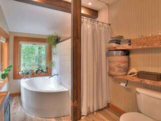Experience tranquility in this charming bathroom featuring a deep soaking tub with a picturesque window view of lush greenery.