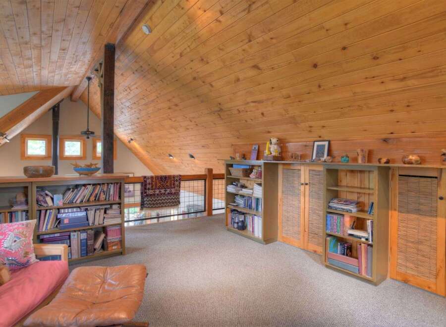 Discover this charming loft space featuring a vaulted, wood-paneled ceiling and exposed beams, creating a warm and inviting atmosphere.