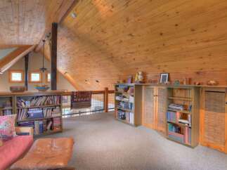 Discover this charming loft space featuring a vaulted, wood-paneled ceiling and exposed beams, creating a warm and inviting atmosphere.