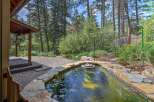 Discover a serene backyard oasis featuring a natural stone-lined pond, perfect for tranquil moments.