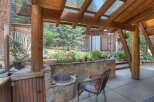 Enjoy outdoor living in this charming covered patio space, featuring a built-in stone grill and a rustic corrugated metal cabinet.