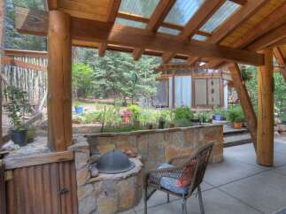 Enjoy outdoor living in this charming covered patio space, featuring a built-in stone grill and a rustic corrugated metal cabinet.