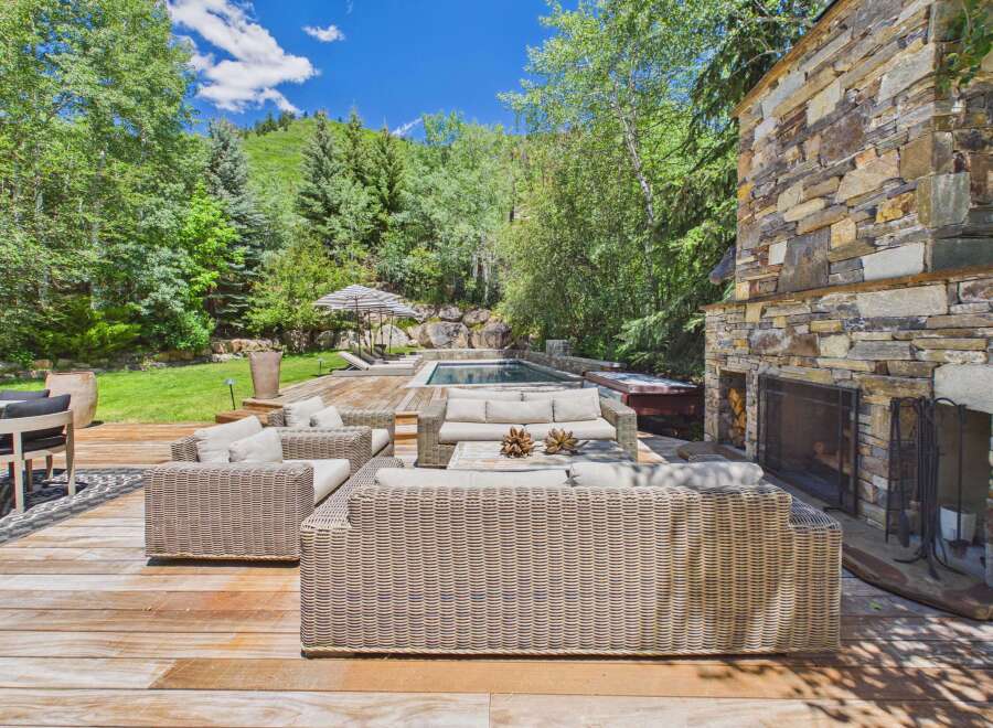 Experience luxurious outdoor living with this stunning deck featuring a cozy seating area, a refreshing pool, and a relaxing hot tub.