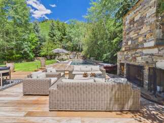 Experience luxurious outdoor living with this stunning deck featuring a cozy seating area, a refreshing pool, and a relaxing hot tub.