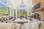 Experience luxury mountain living in this stunning great room, featuring a grand stone fireplace and expansive windows that frame breathtaking panoramic views.