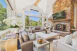 Experience breathtaking mountain views from this stunning living room, featuring a grand stone fireplace and expansive windows.