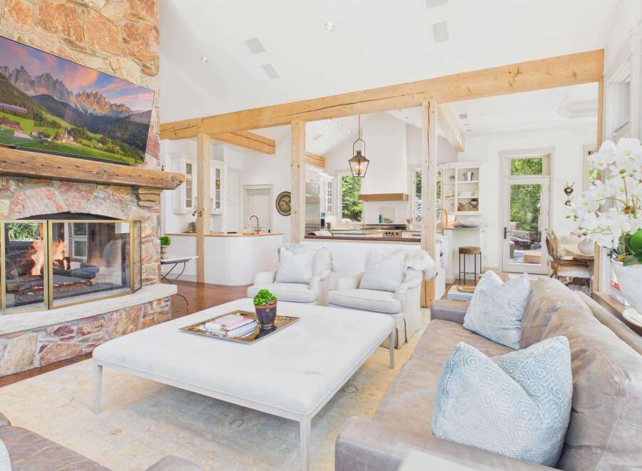 Experience rustic elegance in this spacious living area, featuring a grand stone fireplace and exposed wooden beams that create a warm, inviting atmosphere.