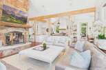 Experience rustic elegance in this spacious living area, featuring a grand stone fireplace and exposed wooden beams that create a warm, inviting atmosphere.