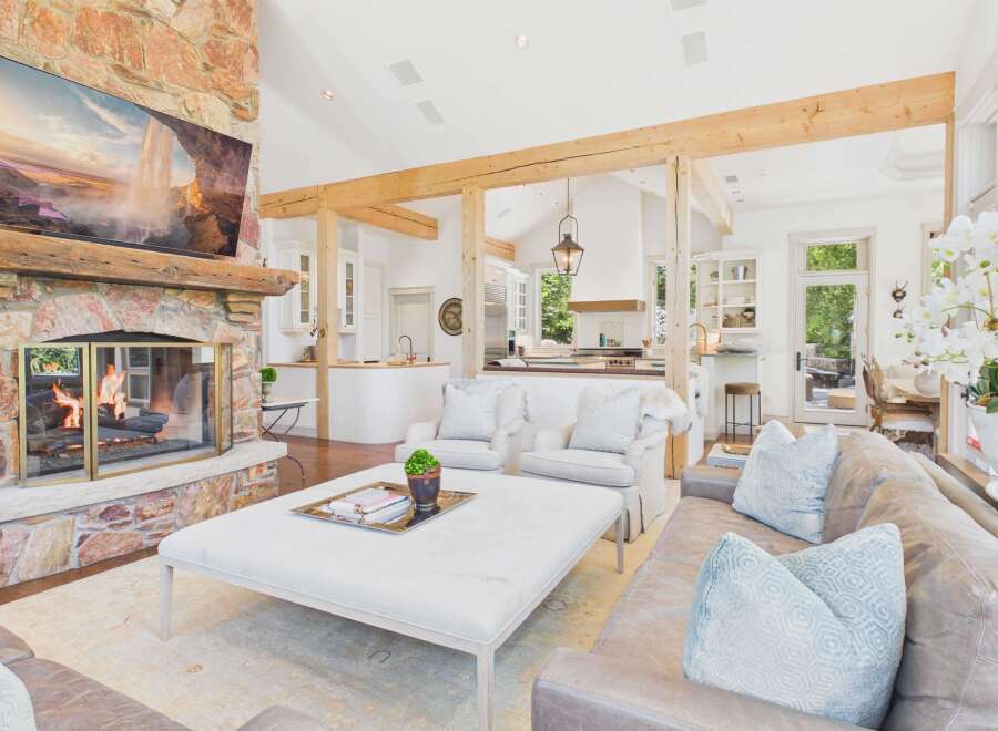 Experience rustic elegance in this spacious living area, featuring a grand stone fireplace and exposed wooden beams that create a warm, inviting atmosphere.