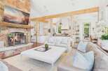 Experience rustic elegance in this spacious living area, featuring a grand stone fireplace and exposed wooden beams that create a warm, inviting atmosphere.