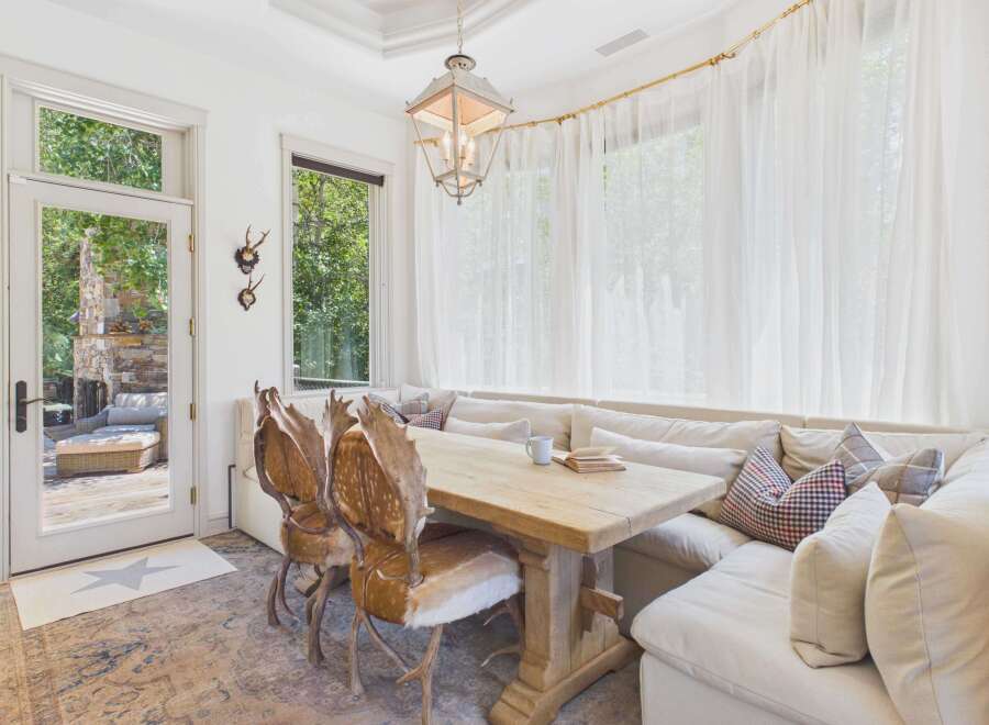 Experience rustic charm in this dining area featuring a live-edge wooden table and unique antler chairs.