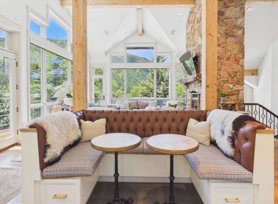 Experience luxurious mountain living in this stunning home featuring a cozy built-in banquette with plush leather upholstery and marble-topped bistro tables.