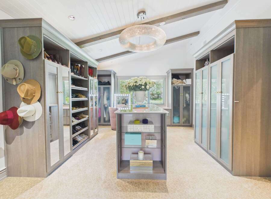 Step into this luxurious walk-in closet, featuring custom grey wood cabinetry with ample storage for shoes and accessories.