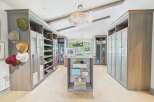 Step into this luxurious walk-in closet, featuring custom grey wood cabinetry with ample storage for shoes and accessories.
