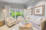 Step into this inviting living room, bathed in natural light from expansive windows overlooking lush greenery.