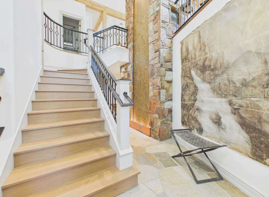Ascend this stunning staircase with light wood treads and a sleek black metal railing, leading to upper levels with elegant curved balconies.