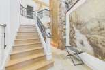Ascend this stunning staircase with light wood treads and a sleek black metal railing, leading to upper levels with elegant curved balconies.