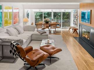 Experience modern living in this stunning open-concept space, featuring a plush sectional sofa and a classic leather lounge chair perfect for relaxation.