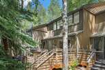 Nestled amongst mature trees, this property offers a serene retreat with its multi-level decks and natural wood siding.