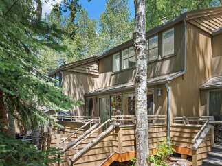 Nestled amongst mature trees, this property offers a serene retreat with its multi-level decks and natural wood siding.