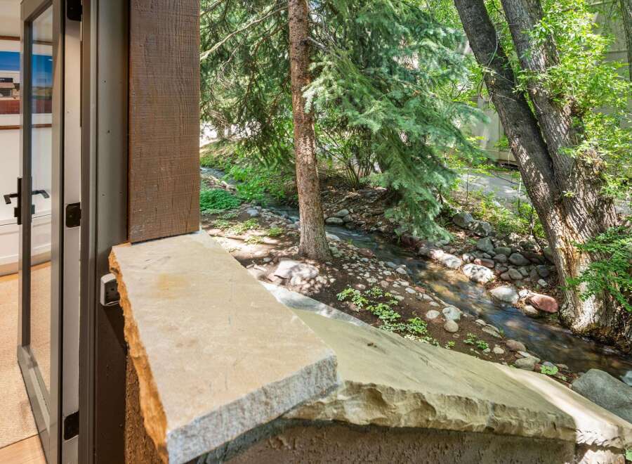 Experience serene living with this stunning property featuring a tranquil stream flowing through lush greenery right outside your door.