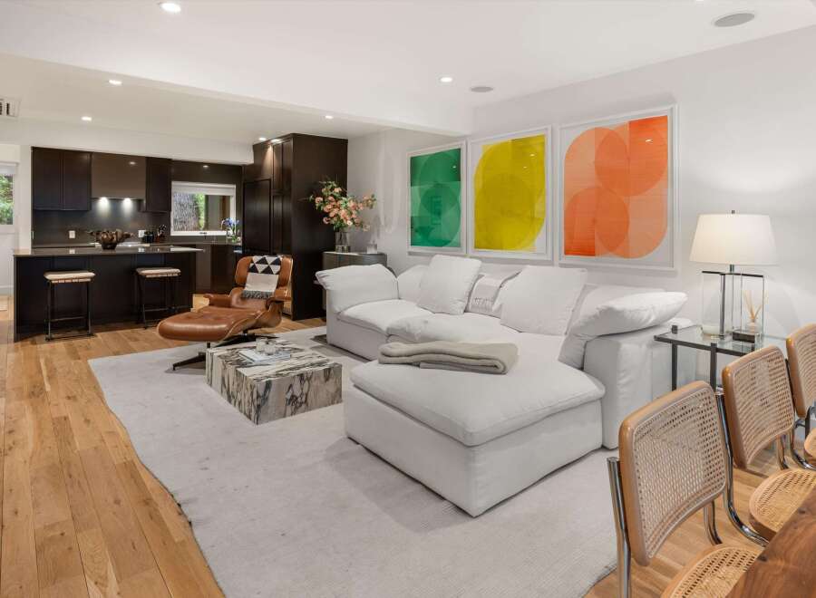 Experience modern living in this open-concept space featuring a sleek dark wood kitchen with a breakfast bar, flowing seamlessly into a bright living area.