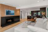 Experience modern living in this stunning open-concept space, featuring a sleek fireplace with a wood-paneled accent wall and a large flat-screen TV.