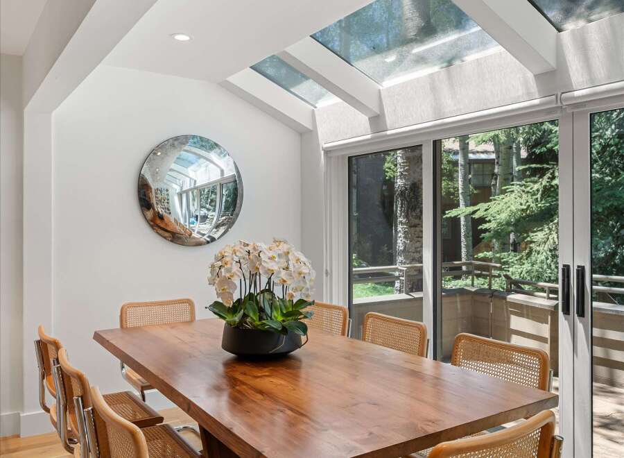 Experience elegant dining in this bright space, featuring a stunning live-edge wood table and comfortable cane-backed chairs.