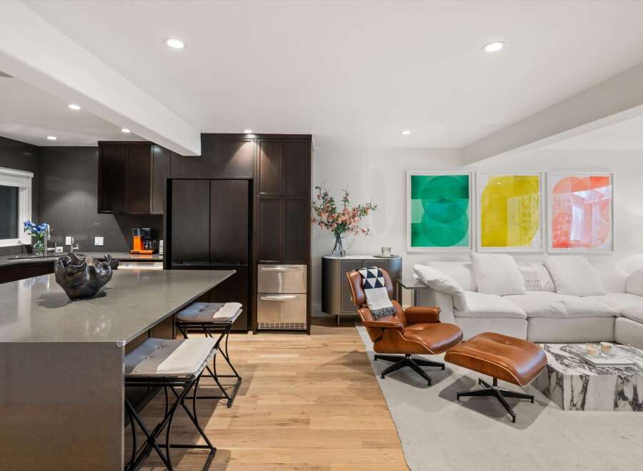 Experience modern living in this open-concept space, featuring a sleek kitchen with dark wood cabinetry and a large island perfect for entertaining.