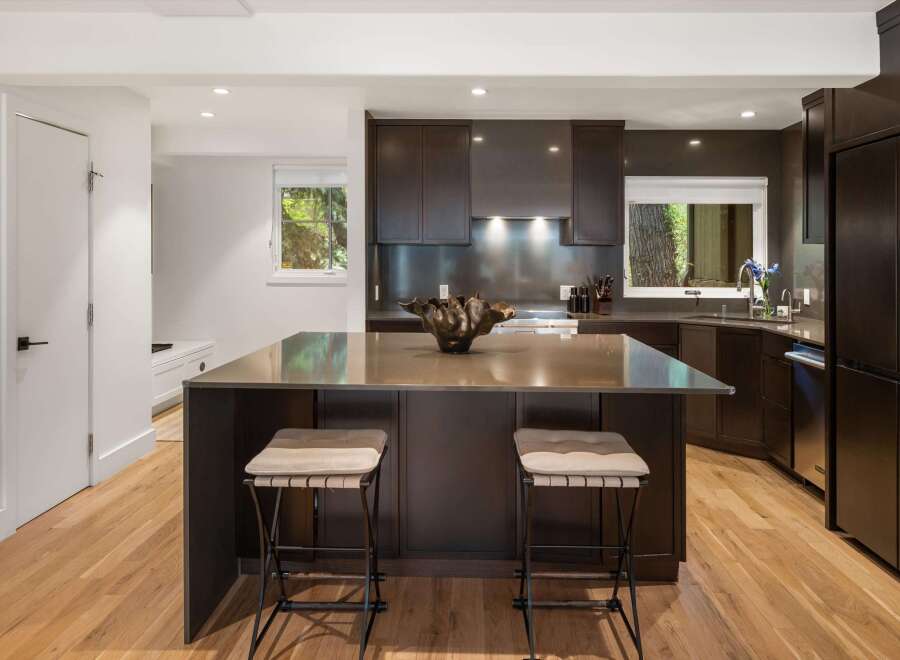Experience modern luxury in this stunning kitchen, featuring sleek dark cabinetry and a spacious island with a metallic countertop.