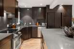Experience luxury in this modern kitchen featuring dark wood cabinetry and sleek gray countertops.