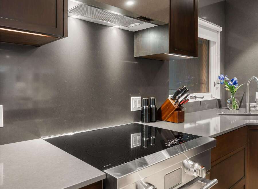 Experience culinary excellence in this modern kitchen, featuring a sleek induction cooktop integrated into a sophisticated quartz countertop.
