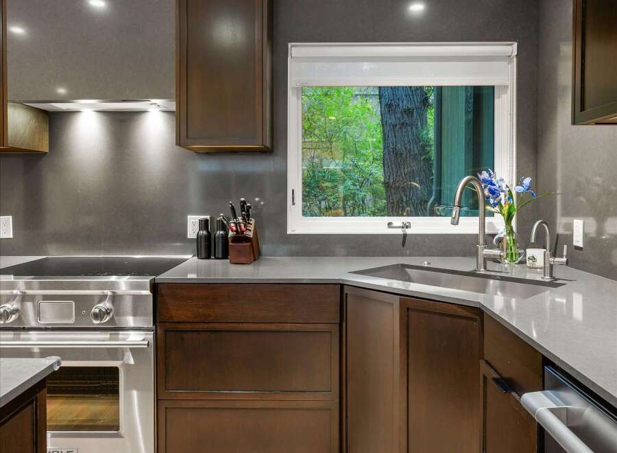 This modern kitchen boasts sleek dark wood cabinetry and a sophisticated gray countertop.