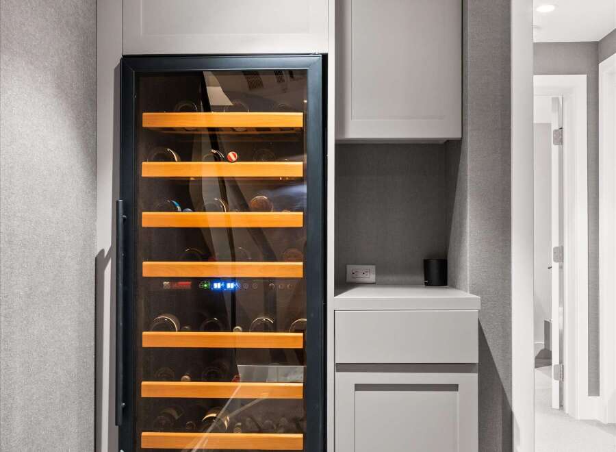 This modern home features a sleek wine cooler integrated into custom cabinetry, perfect for wine enthusiasts.