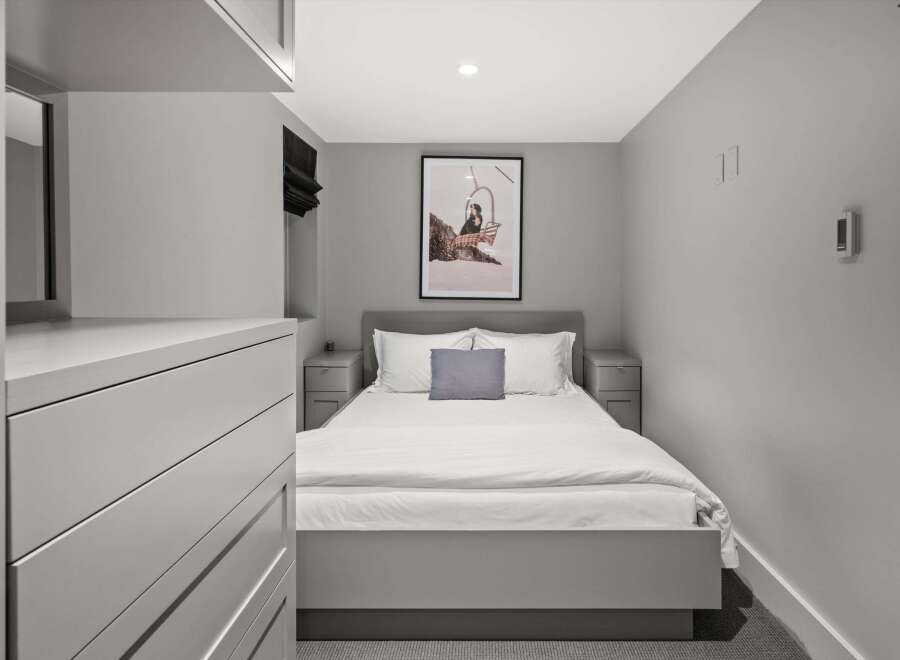 Experience modern comfort in this stylish bedroom, featuring a plush queen-size bed adorned with crisp white linens and a chic grey accent pillow.