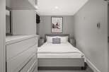 Experience modern comfort in this stylish bedroom, featuring a plush queen-size bed adorned with crisp white linens and a chic grey accent pillow.