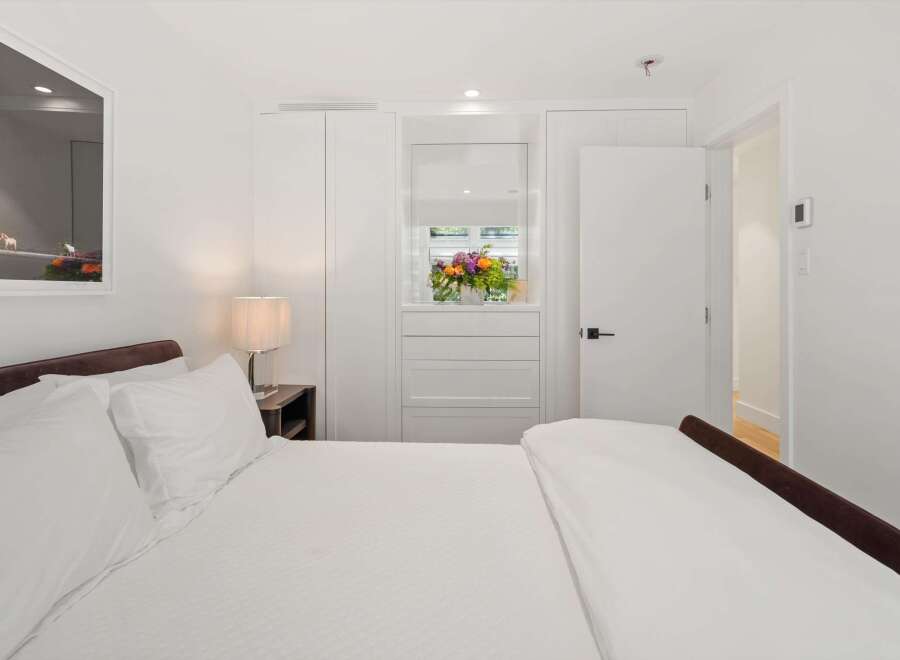 Experience modern comfort in this beautifully appointed bedroom, featuring a plush bed with crisp white linens and a stylish bedside lamp.