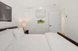 Experience modern comfort in this beautifully appointed bedroom, featuring a plush bed with crisp white linens and a stylish bedside lamp.