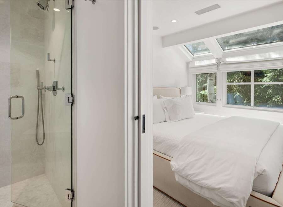Experience modern luxury in this stunning bedroom featuring a plush white bed and large windows that flood the space with natural light.