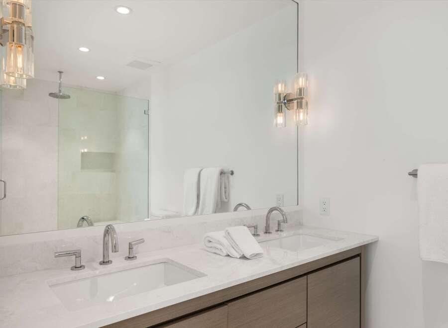 Experience modern luxury in this stunning bathroom, featuring a sleek double vanity with marble countertops and contemporary chrome fixtures.