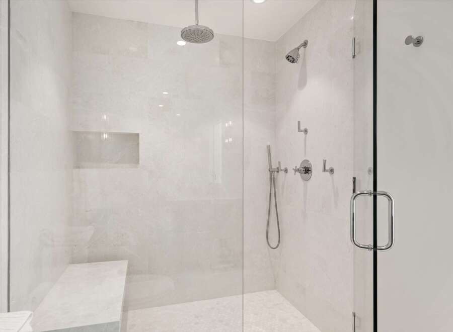 Experience luxury in this modern bathroom featuring a spacious walk-in shower with elegant marble tile and a built-in bench.