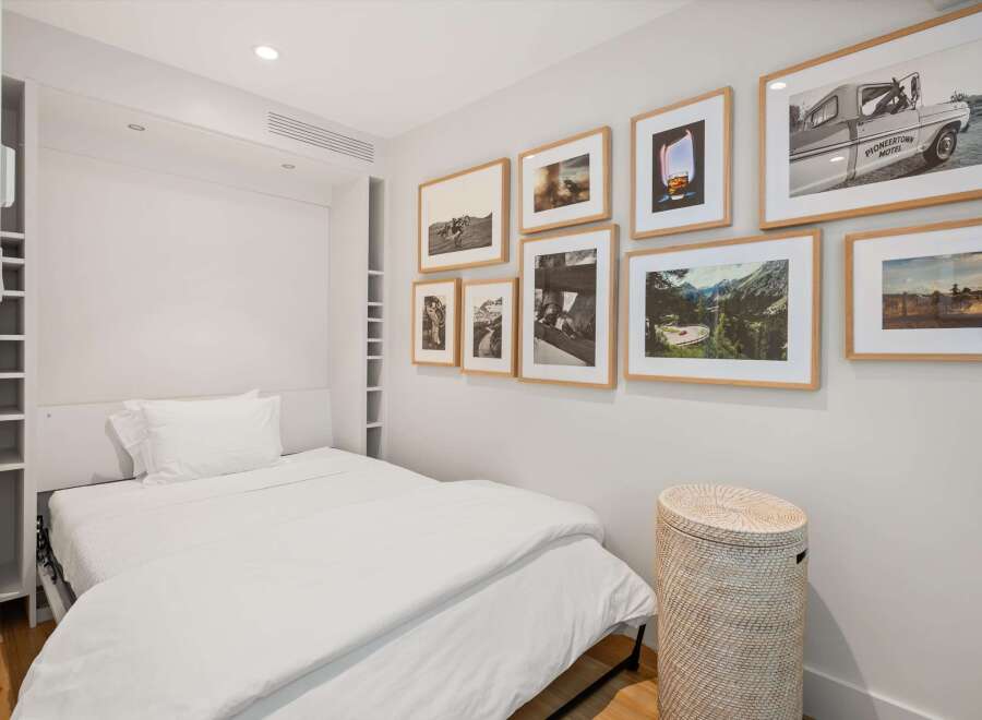 This bedroom features a comfortable bed with crisp white linens, complemented by a collection of framed art on the wall.