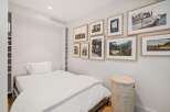 This bedroom features a comfortable bed with crisp white linens, complemented by a collection of framed art on the wall.